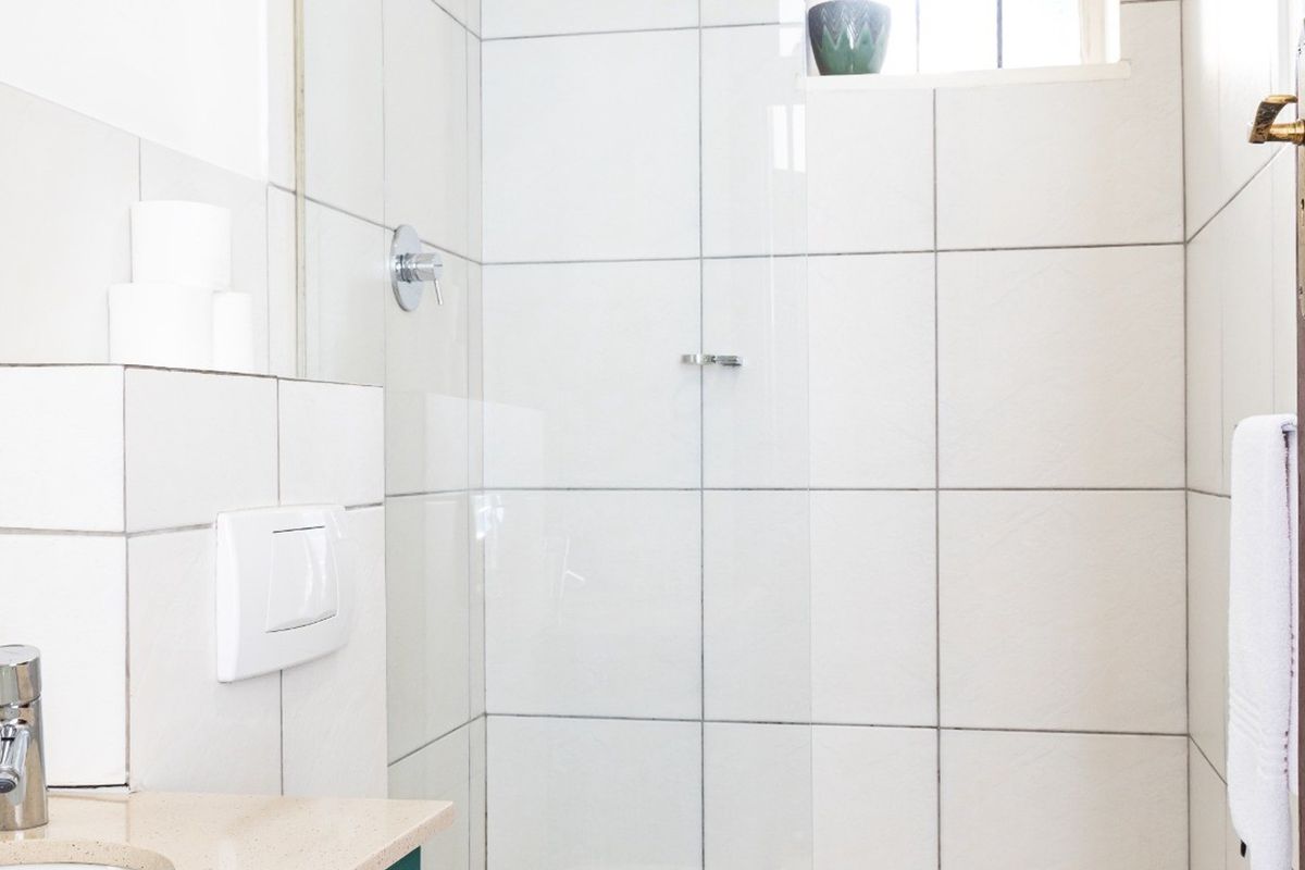 A functional bathroom featuring a glass-enclosed shower, tiled walls, and a vanity basin with modern fixtures.