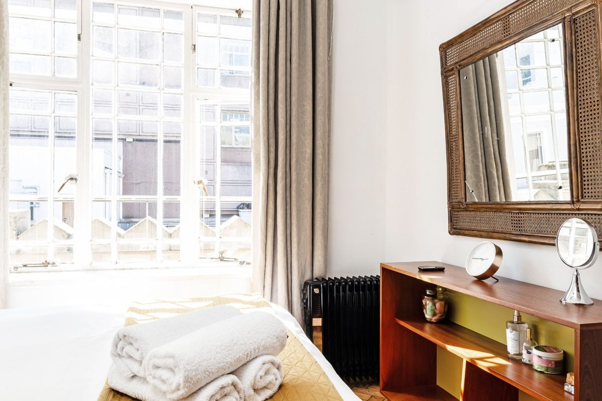 A bright bedroom featuring large multi-pane windows that allow for ample natural light and classic timber flooring.