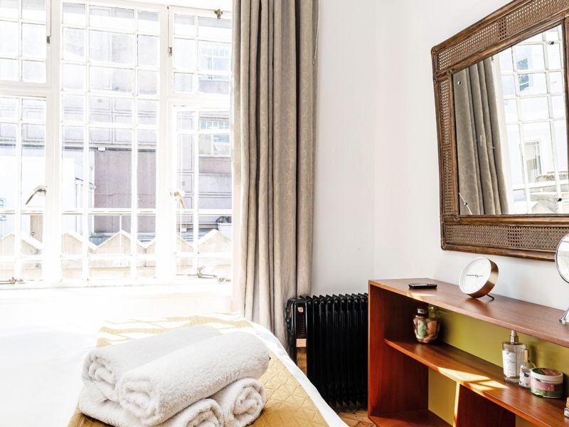 A bright bedroom featuring large multi-pane windows that allow for ample natural light and classic timber flooring.