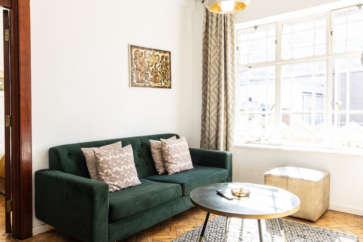 A bright living room featuring classic herringbone timber flooring and a large multi-pane window that allows for ample natural light.