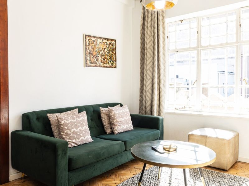 A bright living room featuring classic herringbone timber flooring and a large multi-pane window that allows for ample natural light.