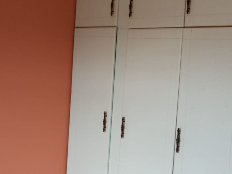 A bedroom featuring white built-in cupboards against a peach-colored wall.