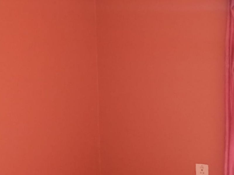 A simple bedroom corner featuring painted walls and an electrical outlet.
