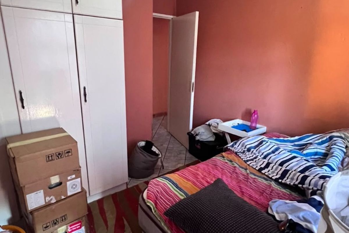 A bedroom featuring built-in cupboards and tiled flooring, providing a functional space with potential for modernization.