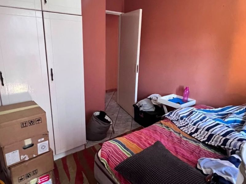 A bedroom featuring built-in cupboards and tiled flooring, providing a functional space with potential for modernization.