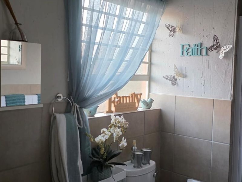 A functional bathroom featuring tiled walls, a shower enclosure, and a window with natural light.