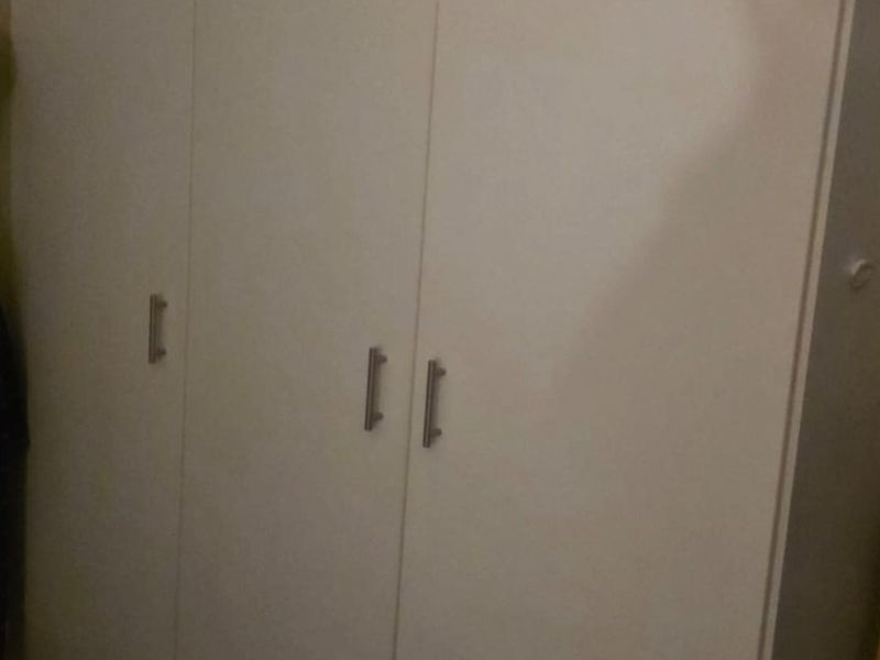 A bedroom featuring a white built-in wardrobe with modern handles.
