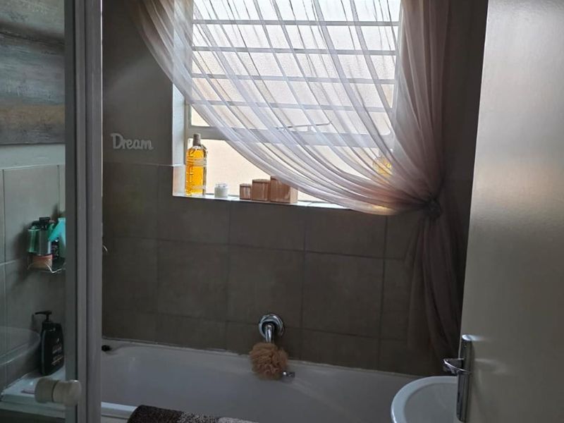 A functional bathroom featuring a bathtub, tiled walls, and a window with security bars, providing a practical space for daily use.