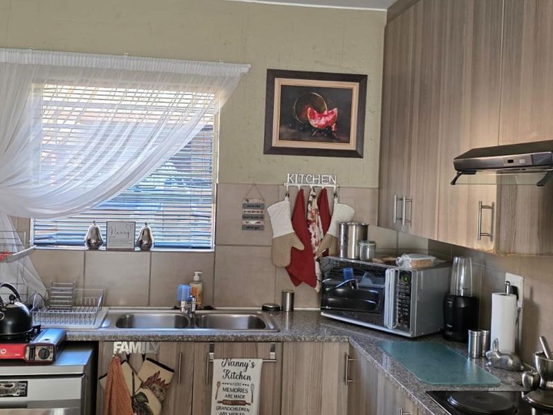 Functional kitchen featuring laminate cabinetry, granite countertops, a double bowl stainless steel sink, and a built-in hob with an extractor fan.