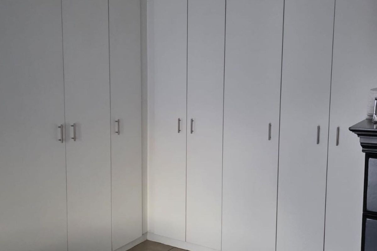 A bedroom featuring extensive white built-in cupboards providing ample storage space.