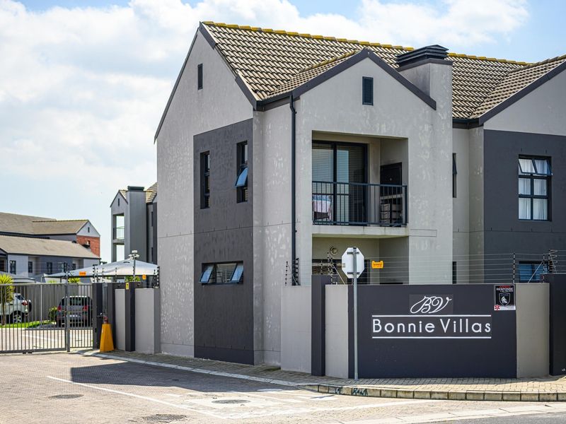 Front elevation of Bonnie Villas apartment complex featuring modern architectural design, secure gated access, and paved driveway.