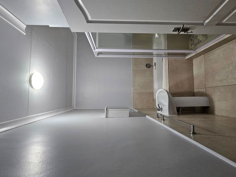 A clean, modern bathroom featuring neutral wall tiles, a glass shower enclosure, and contemporary fixtures. The space is well-maintained and ready for use.