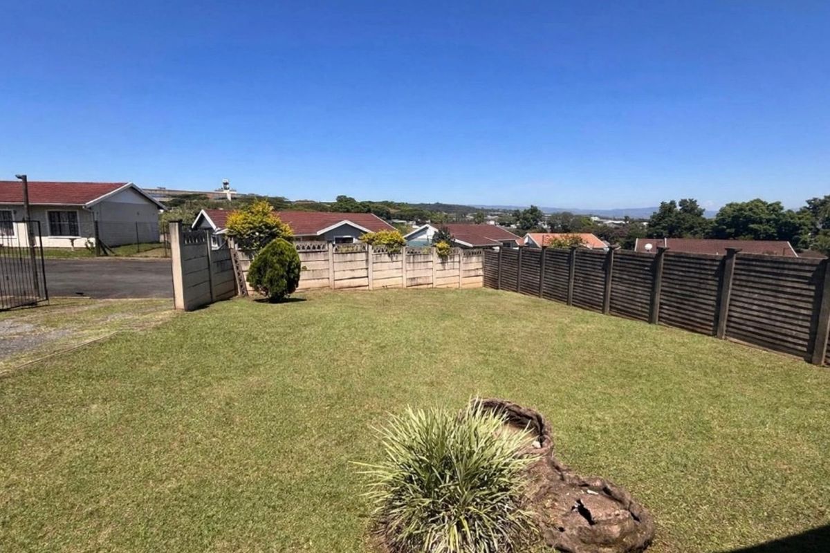 A spacious, level backyard featuring a well-maintained lawn and secure precast concrete boundary walling.