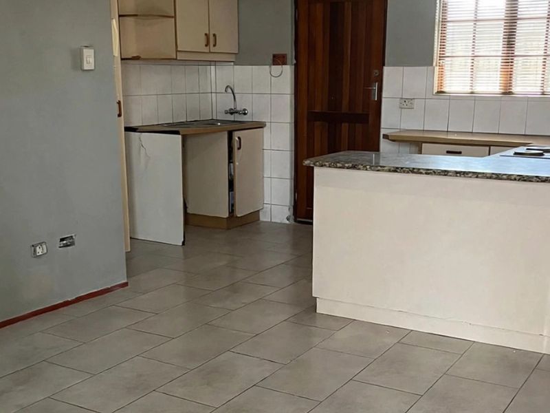 A dated kitchen area featuring built-in cabinetry, a stone countertop, and a hob, currently in need of cosmetic updates and repairs.