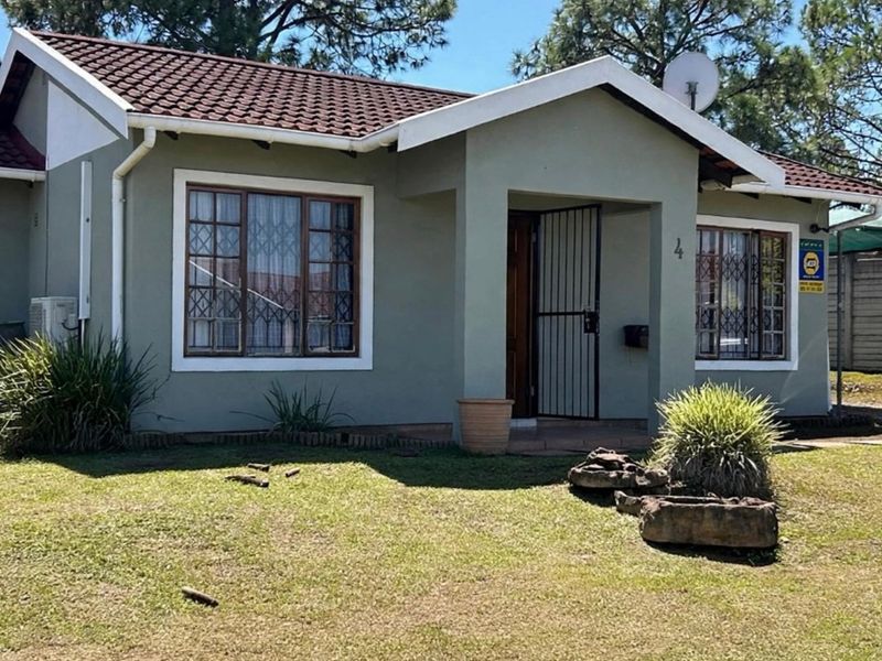 Front elevation of a single-story townhouse featuring a tiled roof, security bars on windows, and a covered entrance area with a security gate.
