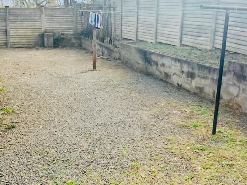 A rear courtyard area featuring a gravel surface, enclosed by precast concrete boundary walls and a low retaining wall.