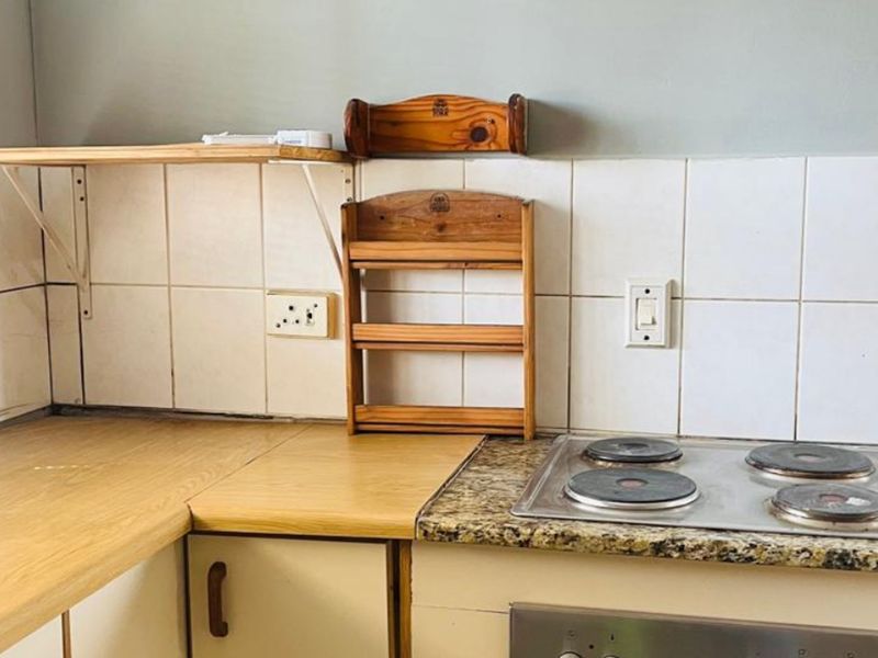A functional kitchen area featuring a combination of laminate and granite countertops, an electric hob, built-in oven, and tiled backsplash.