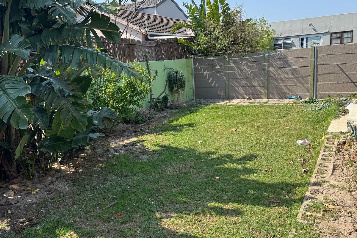 A private rear garden featuring a lawn area, precast concrete boundary walls, and a fixed washing line.