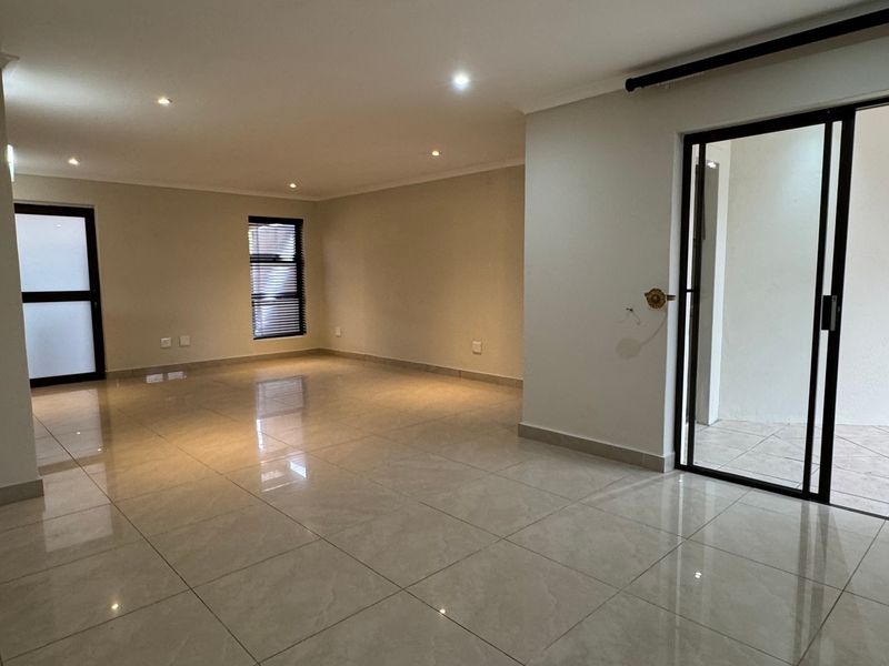 Spacious, empty living area featuring neutral porcelain floor tiles, recessed lighting, and direct access to an outdoor patio through a sliding glass door.