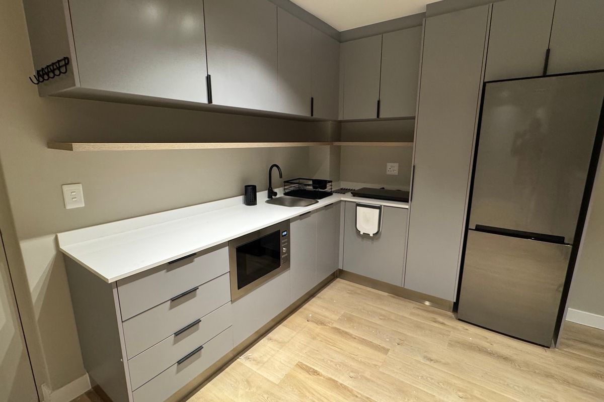Modern kitchen featuring sleek grey cabinetry, stone countertops, integrated microwave, and high-quality laminate flooring in a clean, contemporary design.