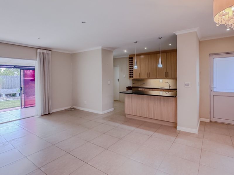 Spacious open-plan living and kitchen area featuring tiled floors, modern cabinetry, granite countertops, and direct access to the outdoor patio through sliding glass doors.