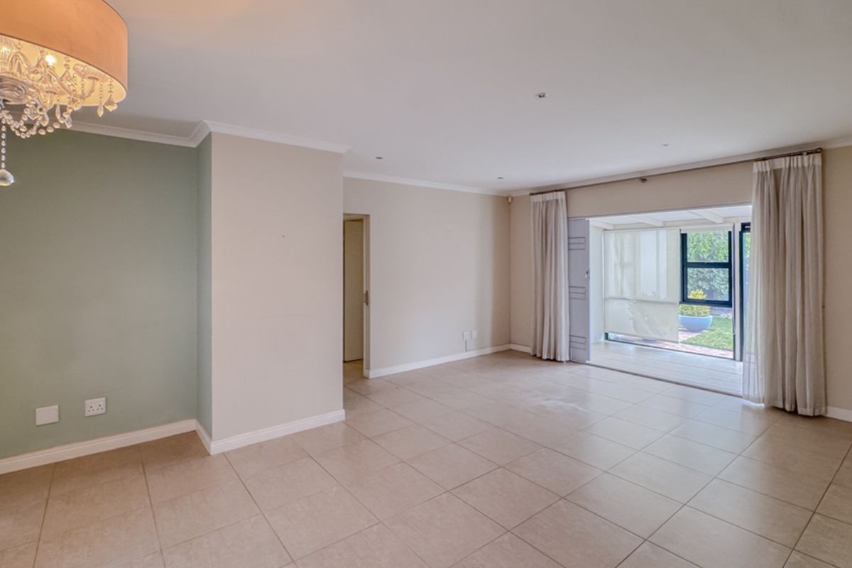 A bright, open-plan living area featuring neutral tiled flooring, recessed lighting, and large sliding glass doors providing direct access to the outdoor patio.