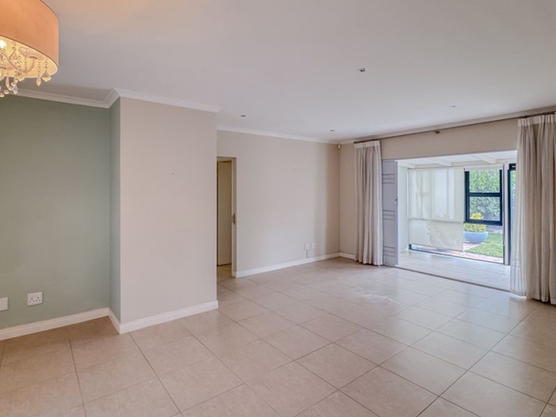 A bright, open-plan living area featuring neutral tiled flooring, recessed lighting, and large sliding glass doors providing direct access to the outdoor patio.