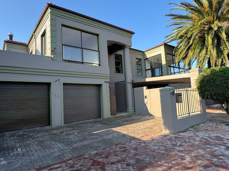 Front elevation of a double-story residence featuring a double garage, paved driveway, and a balcony with architectural columns.