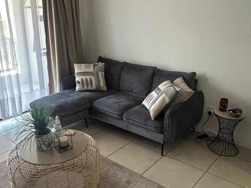 A bright living room featuring neutral tiled flooring and a sliding glass door providing access to an outdoor area.