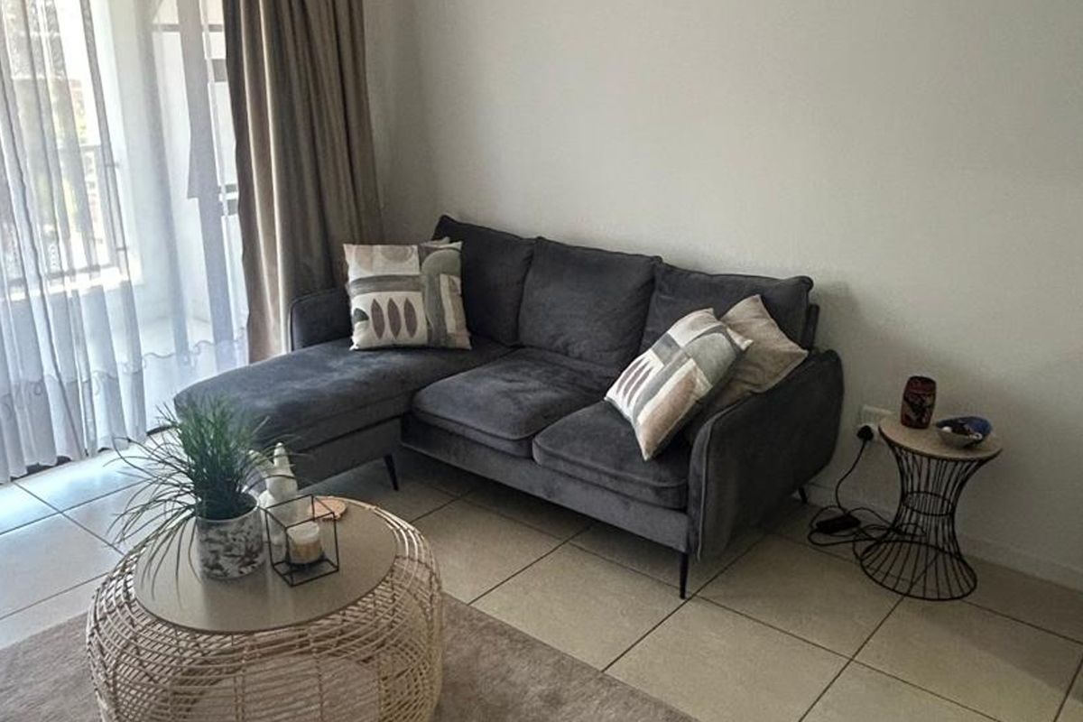 A bright living room featuring neutral tiled flooring and a sliding glass door providing access to an outdoor area.
