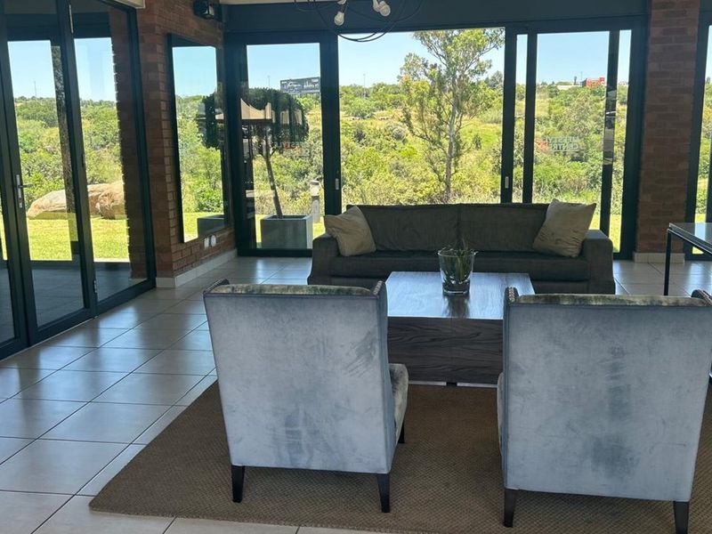 Spacious living area featuring exposed brick walls, large aluminium sliding doors, and expansive views of the surrounding landscape.
