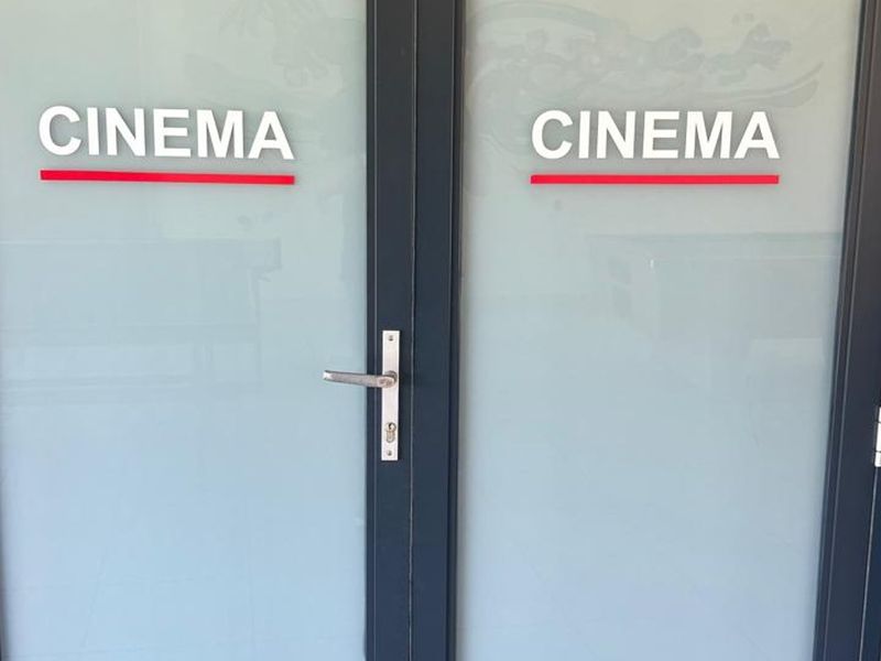 A set of modern frosted glass double doors providing access to the building's dedicated cinema room facility.