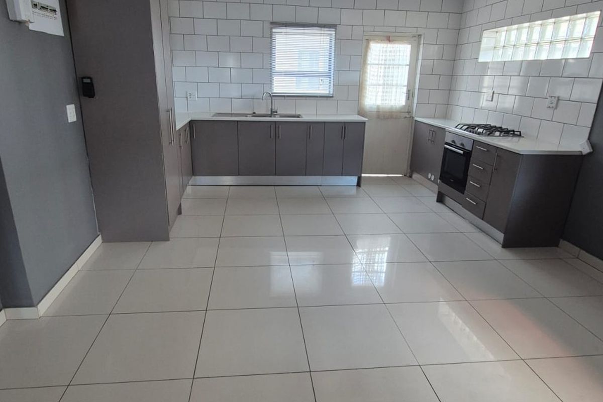 Modern kitchen featuring grey cabinetry, subway tile backsplash, built-in oven, gas hob, and neutral tiled flooring in an open-plan layout.