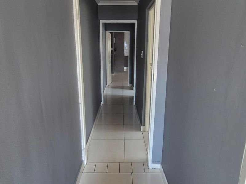A simple interior hallway featuring tiled flooring and dark grey painted walls, providing access to multiple rooms within the property.