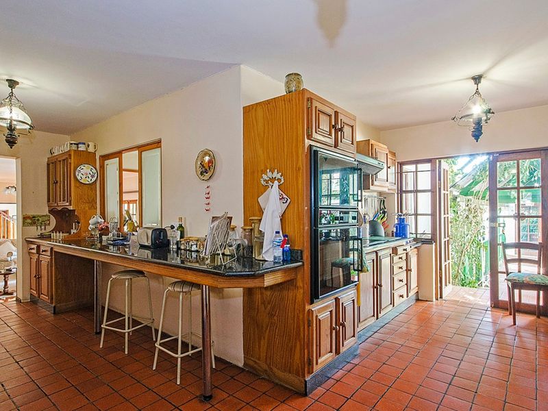 Spacious kitchen featuring traditional wooden cabinetry, granite countertops, built-in double oven, and direct access to the outdoor area through french doors.