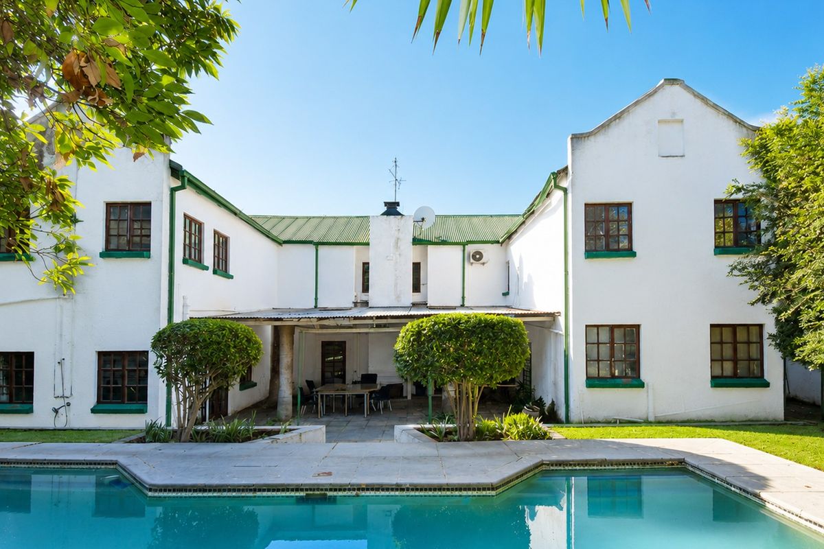 Rear view of the house featuring a swimming pool, a covered patio area, and a white facade with green trim.