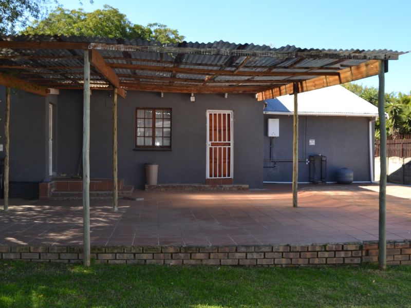 A covered outdoor patio area featuring tiled flooring, a corrugated iron roof structure, and direct access to the cottage exterior.