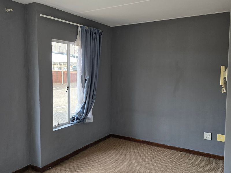 An empty bedroom featuring grey painted walls, carpet flooring, and an integrated intercom system.
