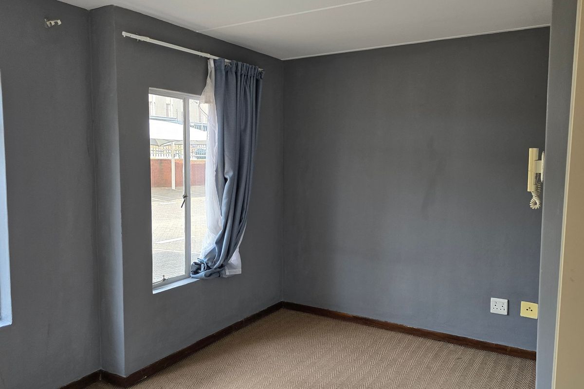 An empty bedroom featuring grey painted walls, carpet flooring, and an integrated intercom system.