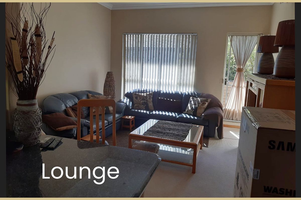 A living room area featuring carpet flooring, vertical blinds, and access to an outdoor space through a glass door.
