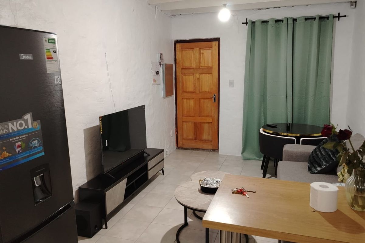 A compact living area featuring tiled flooring and textured walls, providing a functional space with direct access to an exterior door.