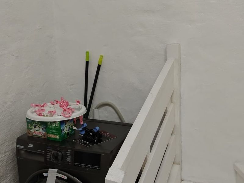 A functional laundry area featuring a built-in washing machine and painted masonry walls, providing a practical space for household utility tasks.
