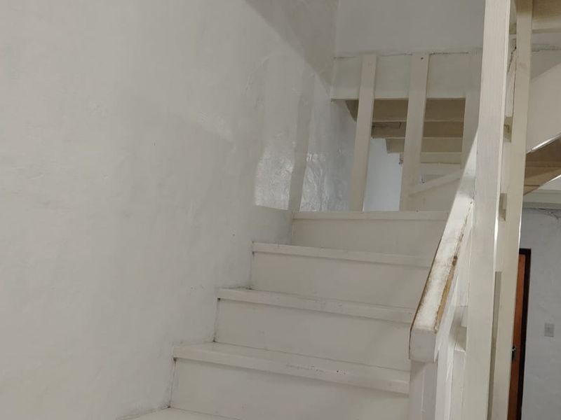 A simple interior staircase with painted timber balustrades and handrails, showing signs of wear and requiring cosmetic updates.