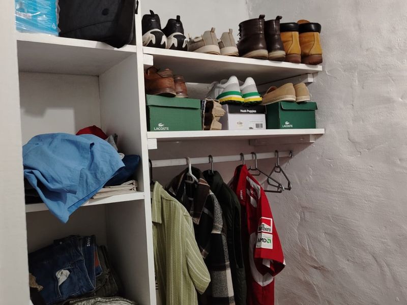 A utility storage space featuring built-in shelving and a hanging rail for organized storage.