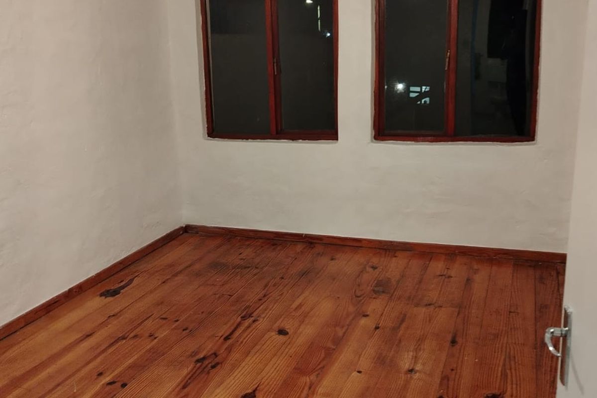 An empty bedroom featuring original timber flooring and wooden window frames, offering a blank canvas for personalization.