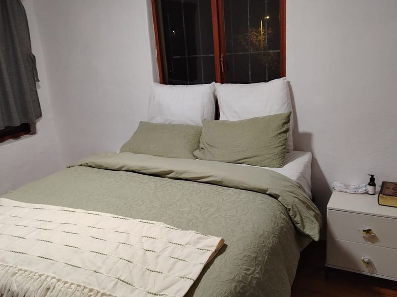 A bedroom featuring a window with security bars and wooden frames, requiring minor cosmetic updates to the wall finishes and window frames.