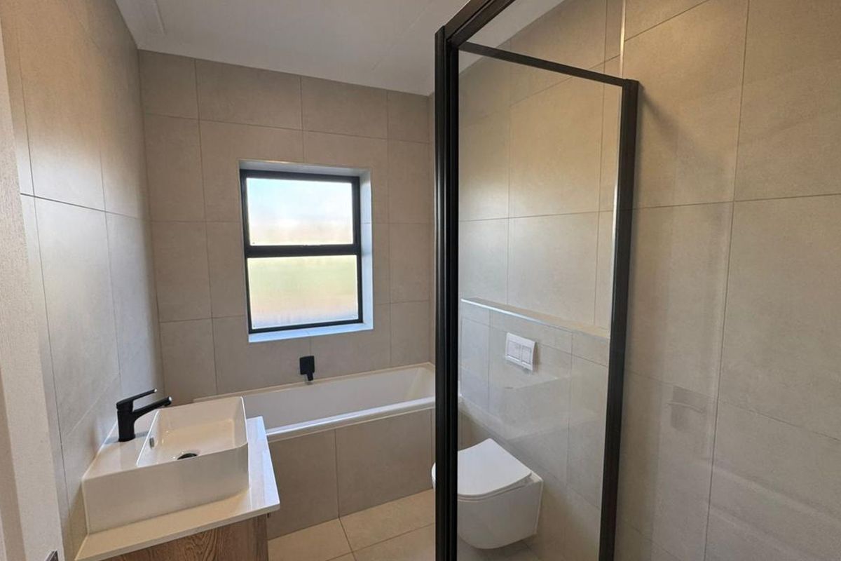 Modern bathroom featuring a built-in bathtub, wall-mounted toilet, shower enclosure, and contemporary vanity with black fixtures and neutral wall tiling.