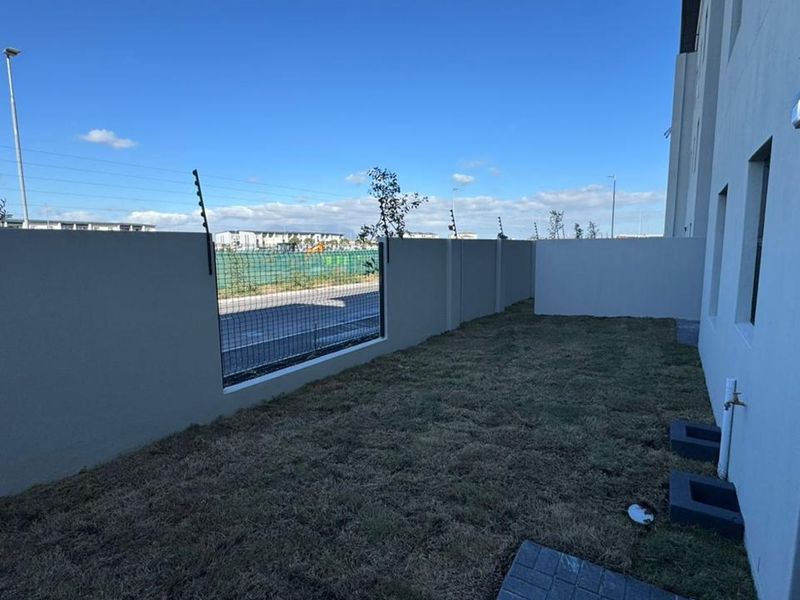 A private rear garden area featuring a perimeter wall with electric fencing, an outdoor tap, and external wall lighting.