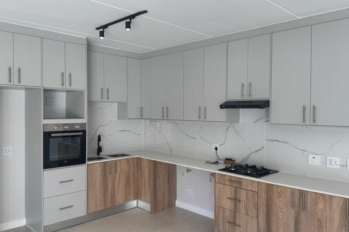 Modern kitchen featuring two-tone cabinetry, marble-look splashback, quartz countertops, built-in oven, gas hob, and integrated extractor fan.