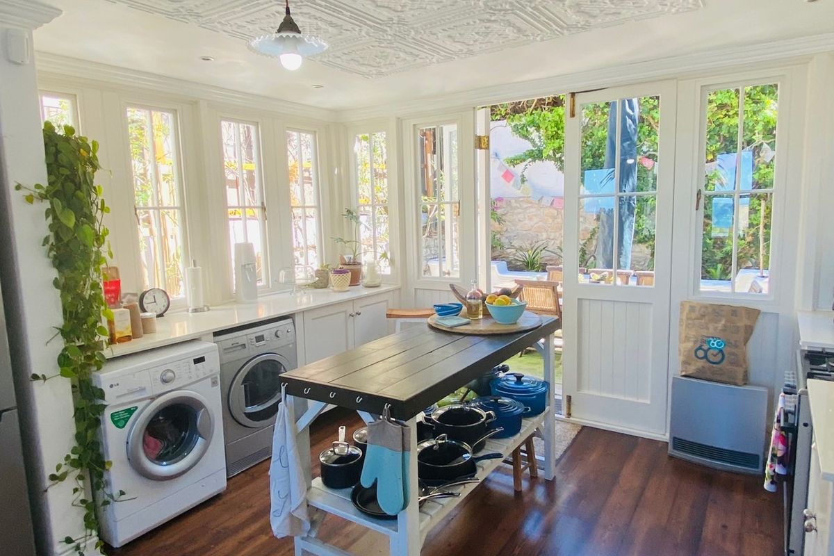 Bright kitchen featuring white cabinetry, timber flooring, and a decorative ceiling, with direct access to the outdoor patio area through glass french doors.
